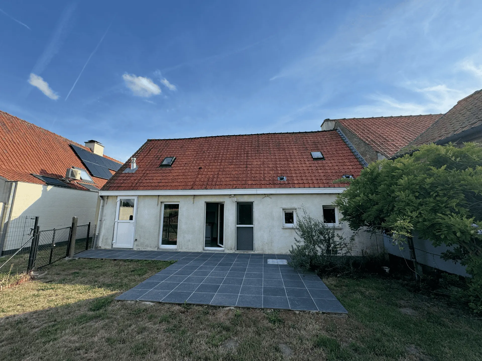 Achtergevel van de woning met terras en grote tuin